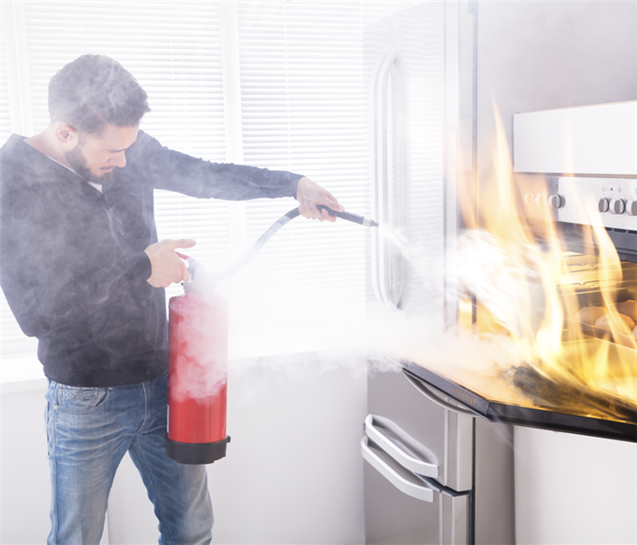 A man trying to put out an oven with rising flames.